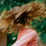 Foto zum Beitrag über Rollenbilder in der Schule: Ein Kind mit langen Haaren, das sich dreht, fliegende Haare sind zu sehen
