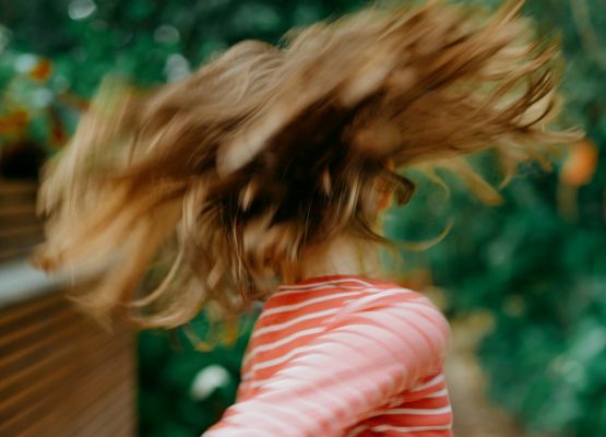 Foto zum Beitrag über Rollenbilder in der Schule: Ein Kind mit langen Haaren, das sich dreht, fliegende Haare sind zu sehen