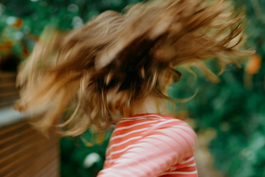 Foto zum Beitrag über Rollenbilder in der Schule: Ein Kind mit langen Haaren, das sich dreht, fliegende Haare sind zu sehen