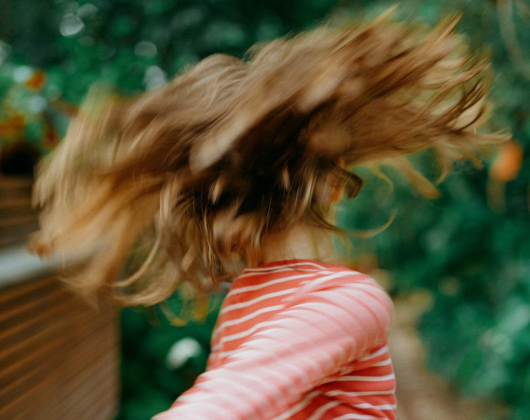 Foto zum Beitrag über Rollenbilder in der Schule: Ein Kind mit langen Haaren, das sich dreht, fliegende Haare sind zu sehen